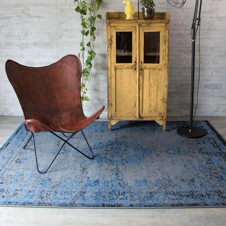 blauw vintage vloerkleden met lederen fauteuil en gele houten kast