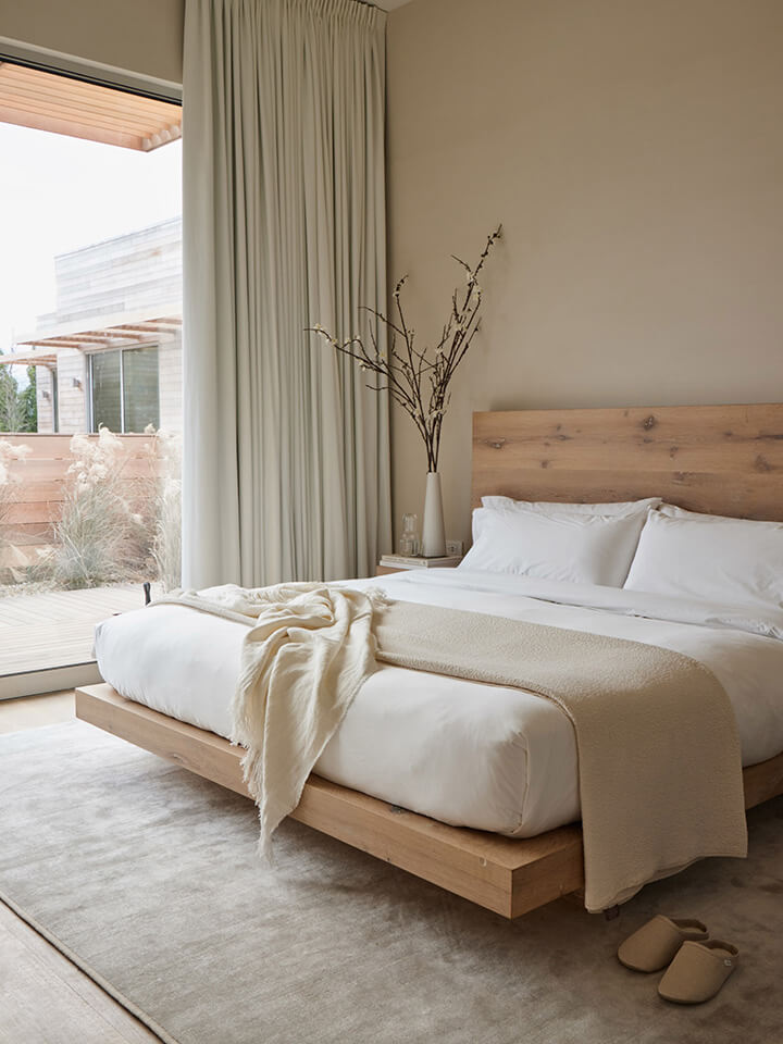 houten bed met witte lakens en tapijt